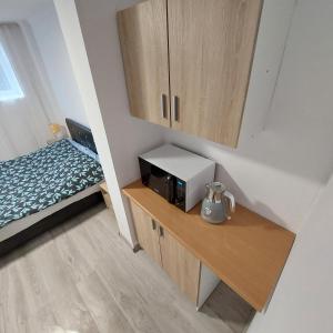 Kleines Zimmer mit einer Mikrowelle und einem Bett. in der Unterkunft Szary Domek 2 in Wieprz