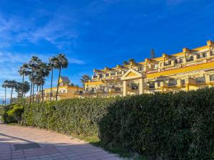 duży żółty budynek z palmami i chodnikiem w obiekcie Modern beach apartment Romana Playa 723 in Marbella, Elviria w Marbelli