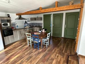 una cucina con tavolo e sedie in legno e una cucina con porte verdi di Cottage entre Terre et Mer a Gouville-sur-Mer