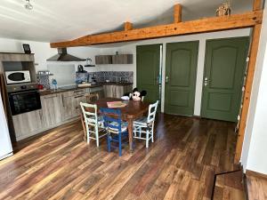 eine Küche mit Holztisch und Stühlen und eine Küche mit grünen Türen in der Unterkunft Cottage entre Terre et Mer in Gouville-sur-Mer + 4 Fotos