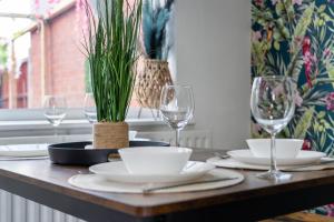 a table with plates and glasses and a plant on it at Exclusive Deals l Last-Minute Reserve l Townhouse with Sleeps 6 l Braunstone Town , Leicester l By Zen Nights Short Lets & Serviced Accommodations in Braunstone