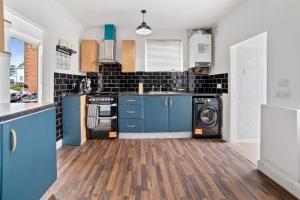 a kitchen with blue cabinets and a washer and dryer at Exclusive Deals l Last-Minute Reserve l Townhouse with Sleeps 6 l Braunstone Town , Leicester l By Zen Nights Short Lets & Serviced Accommodations in Braunstone +15 photos