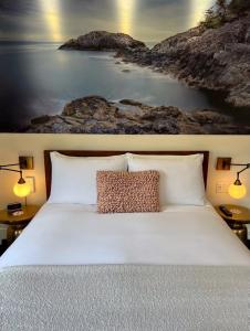 ein Schlafzimmer mit einem Bett mit einem Bild vom Strand in der Unterkunft Artisan Suites on Bowen in Bowen Island