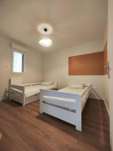 Zimmer mit 2 Betten in einem Zimmer mit Holzböden in der Unterkunft L’escapade in Boulleville