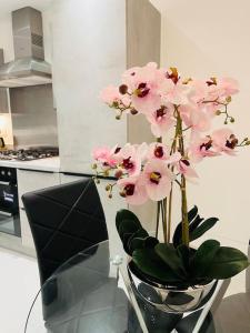 a vase with pink flowers sitting on a glass table at Luxurious modern new built 4 bedrooms in Manchester