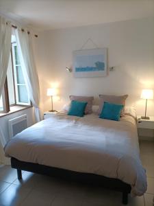 ein Schlafzimmer mit einem großen weißen Bett mit blauen Kissen in der Unterkunft Le Petit Nid de Nant in Nant