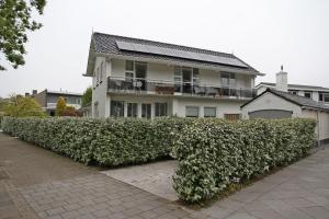 a large hedge in front of a white house at Appartement Mooi Plekje Vlissingen in Vlissingen