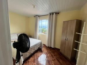 una camera da letto con ventilatore su un letto e una finestra di Casa em Ilha Grande - João da Mariana ad Angra dos Reis