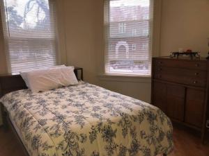 a bedroom with a bed and a dresser and two windows at Walk to Downtown Salem in Salem