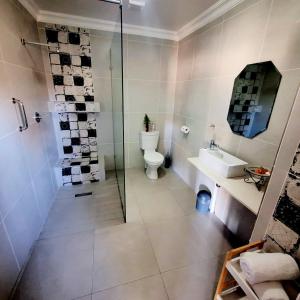 uma casa de banho com um chuveiro, um WC e um lavatório. em Paradise View Guesthouse em Graskop