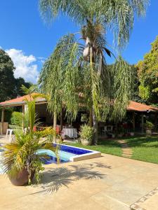 una casa con una palmera y una piscina en Hotel Fazenda Tia Dora en Três Marias