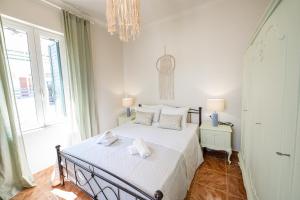 a bedroom with a bed with white sheets and a chandelier at Sunny yard apartments in Poros