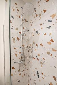 a shower in a bathroom with a stone wall at Sunny yard apartments in Poros