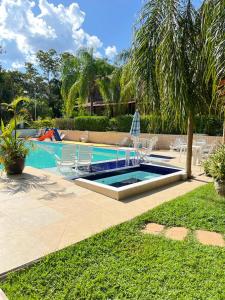 a swimming pool with two chairs and a table at Hotel Fazenda Tia Dora in Três Marias