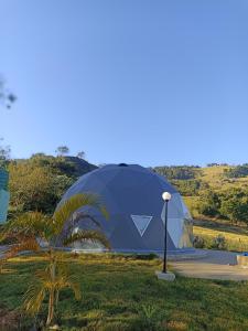 ein großes Kuppelzelt auf einem Feld mit einer Palme in der Unterkunft Domo geodésico_conforto e relaxamento na natureza in Socorro