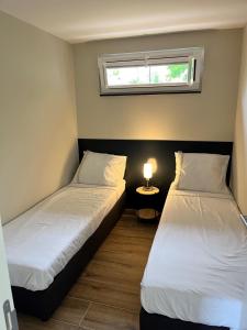 two beds in a room with a table and a window at Oosterschelde Lodge met veel privacy en dicht bij het water in Scherpenisse