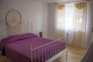 a bedroom with a bed with purple sheets and a window at Casa Natura e Quiete in Stregna