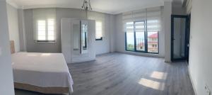 um amplo quarto branco com uma cama e janelas grandes em Kiralık Lüx Deniz Manzaralı Bahçeli Villa/Luxury Sea View Garden Villa for Rent em Trabzon
