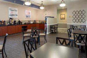 a dining room with tables and chairs and a kitchen at Grandstay Apple Valley in Apple Valley