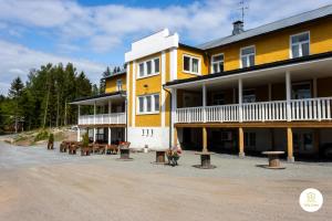 un gran edificio amarillo con mesas de picnic y bancos en Villa Eden - Design-Sea-Pool-Sauna-Services, en Kemiönsaari