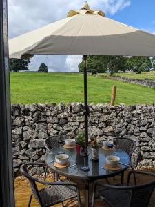 a table with an umbrella on a patio at Primrose Cottage - Tideswell, Peak District in Tideswell