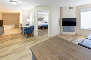 アップル・バレーにあるGrandstay Apple Valleyのベッド、テレビ、リビングルームが備わるホテルルームです。