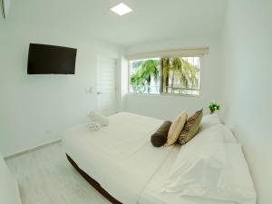 a white bedroom with a large white bed with a window at Hotel Koray in San Andrés
