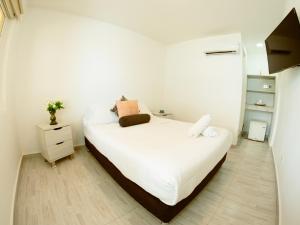 a bedroom with a white bed and a wooden floor at Hotel Koray in San Andrés