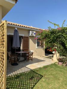 une terrasse avec une table et un parasol dans l'établissement House with Garden in Peratata - 10' from City Center, à Peratáta