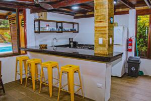 a kitchen with yellow stools at a counter at Casa Sua--Cozy 3 Bedroom Dominical Beach Cottage with Pool in Dominical