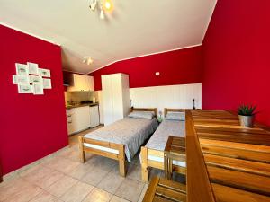 um quarto vermelho com 2 camas e uma mesa de jantar em Studio Apartma Olive, Nova Gorica, Slovenia em Nova Gorica