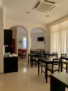 a dining room with tables and chairs and a kitchen at Hotel Vila Verde in Castro Verde