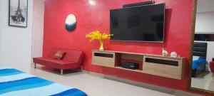 a living room with a tv on a red wall at Casa con Piscina Privada Playas del Mar in Cartagena de Indias