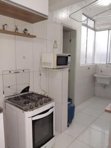 a white kitchen with a stove and a microwave at Apto Stiep Inteiro in Salvador