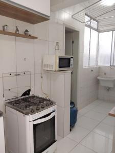 cocina blanca con fogones y microondas en Apto Stiep Inteiro, en Salvador