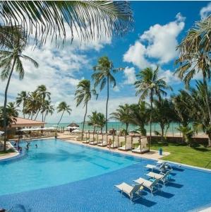 basen w ośrodku z palmami i oceanem w obiekcie JATIÚCA SUITES RESORT - Flat VISTA MAR w mieście Maceió