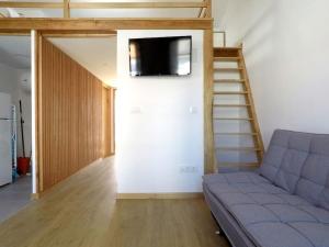 ein Wohnzimmer mit einem Sofa und einem TV an der Wand in der Unterkunft Ferreiros - Wood Design apartments in Puentedeume