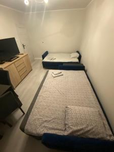 a small room with two beds and a tv at Apartament na Broniewskiego in Gdańsk