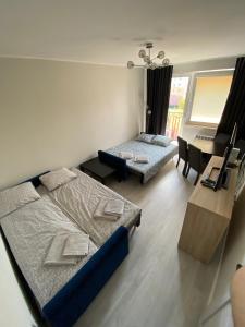 a bedroom with two beds and a desk and a table at Apartament na Broniewskiego in Gdańsk