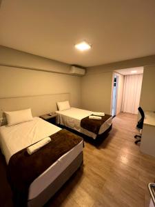 una camera d'albergo con 2 letti e una scrivania di SG Apart Hotel a São Gonçalo do Rio Abaixo