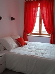 1 dormitorio con 1 cama con cortinas rojas y ventana en La Jolie Dourbie de Nant, en Nant
