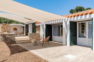 a patio with chairs and an awning on a house at Alcotx Country Club in Es Mercadal