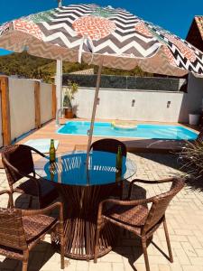 una mesa y sillas bajo una sombrilla junto a una piscina en Casa Brisa do Mar: Piscina e Conforto - Penha, en Penha