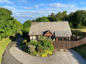 uma casa com uma cerca ao lado de uma estrada em The Lodge at Woodend em Kemnay