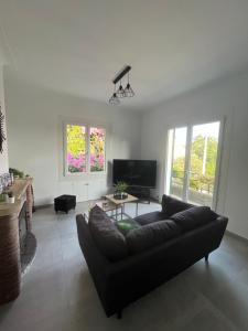 uma sala de estar com um sofá preto e uma televisão em Villa 2 chambres rénovée Juillet 2023 - vue mer - parking privé em Grasse