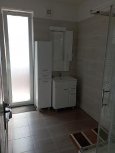 een badkamer met een wastafel en een witte koelkast bij Thaly 5/1 in Debrecen
