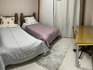 a bedroom with two beds and a desk and a table at Dith's House in Campos do Jordão