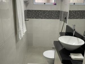 bagno bianco con lavandino e servizi igienici di Dith's House a Campos do Jordão
