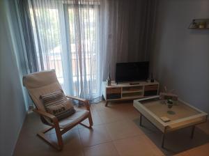 ein Wohnzimmer mit einem Stuhl, einem TV und einem Couchtisch in der Unterkunft Castle View Apartment in Kavala