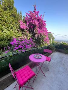 una mesa rosa y sillas en un patio con flores rosas en Villa 2 chambres rénovée Juillet 2023 - vue mer - parking privé en Grasse